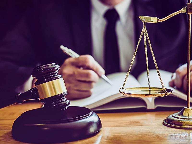 Male lawyer working with contract papers with balance scale and gavel.
