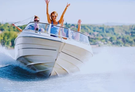 Group of young people with raised hands enjoying in a speedboat ride.