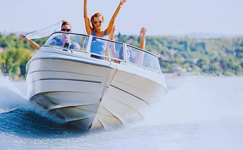 Group of young people with raised hands enjoying in a speedboat ride.