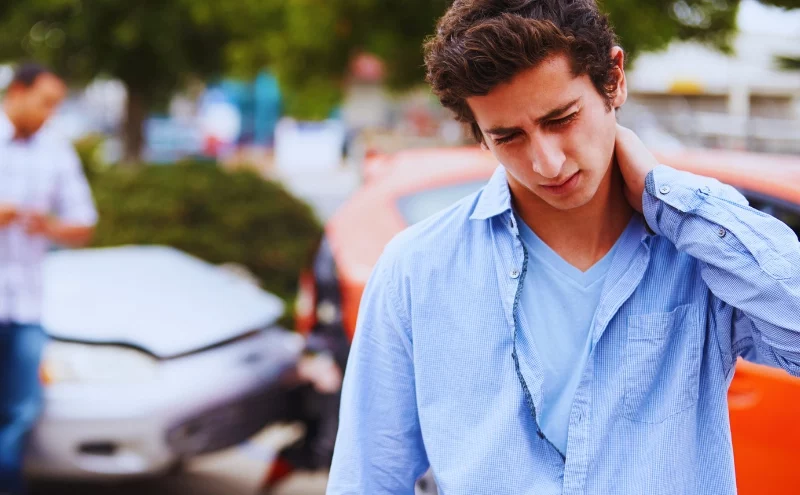 young man rubbing injured neck, representing a motor vehicle accident injury